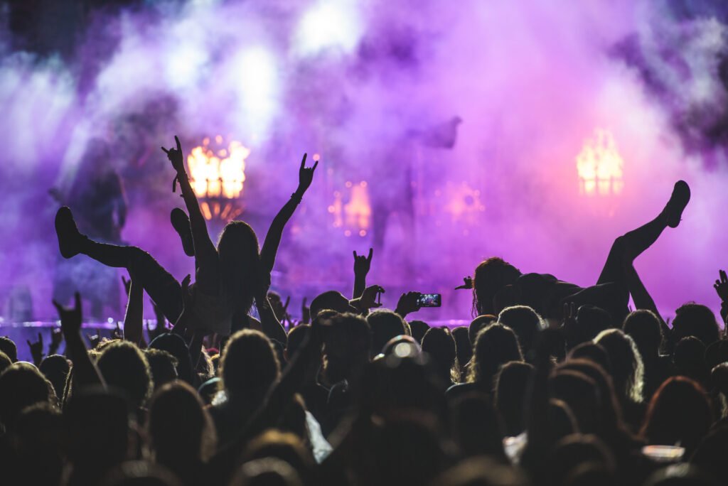 Silhouette of a crowd on a rock concert while crowd surfing and using smartphone